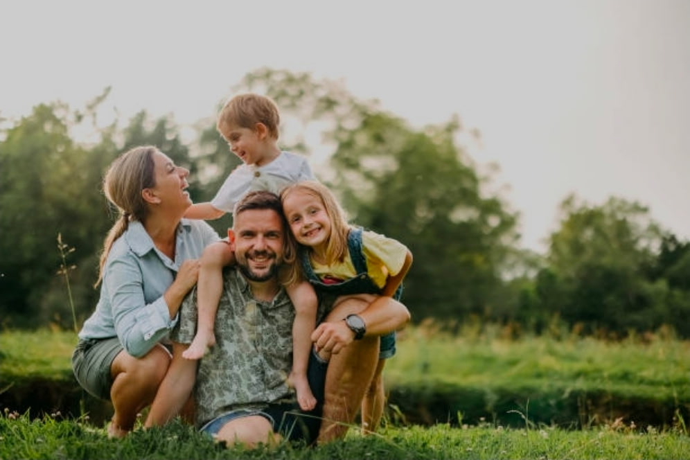 Parents and their two children enjoying a playful moment in a park