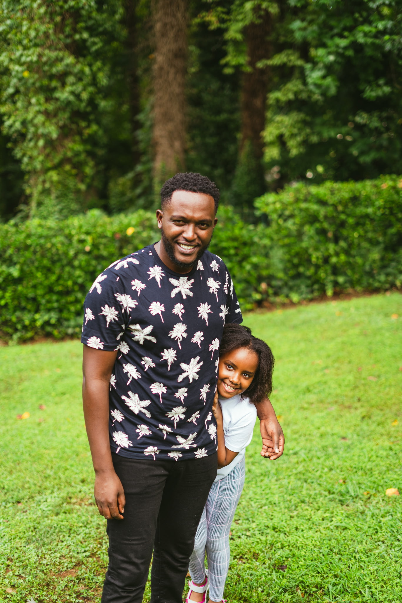 A father and daughter standing together and smiling outdoors
