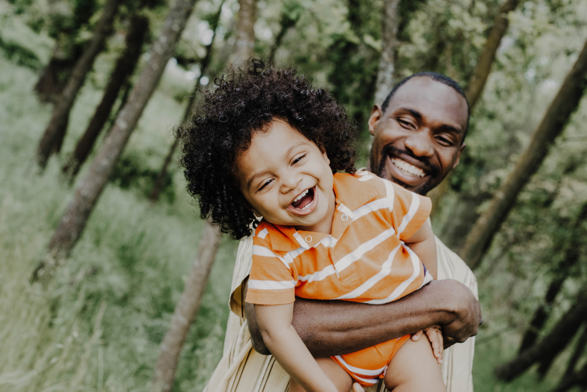 A father holding his laughing young son outdoors