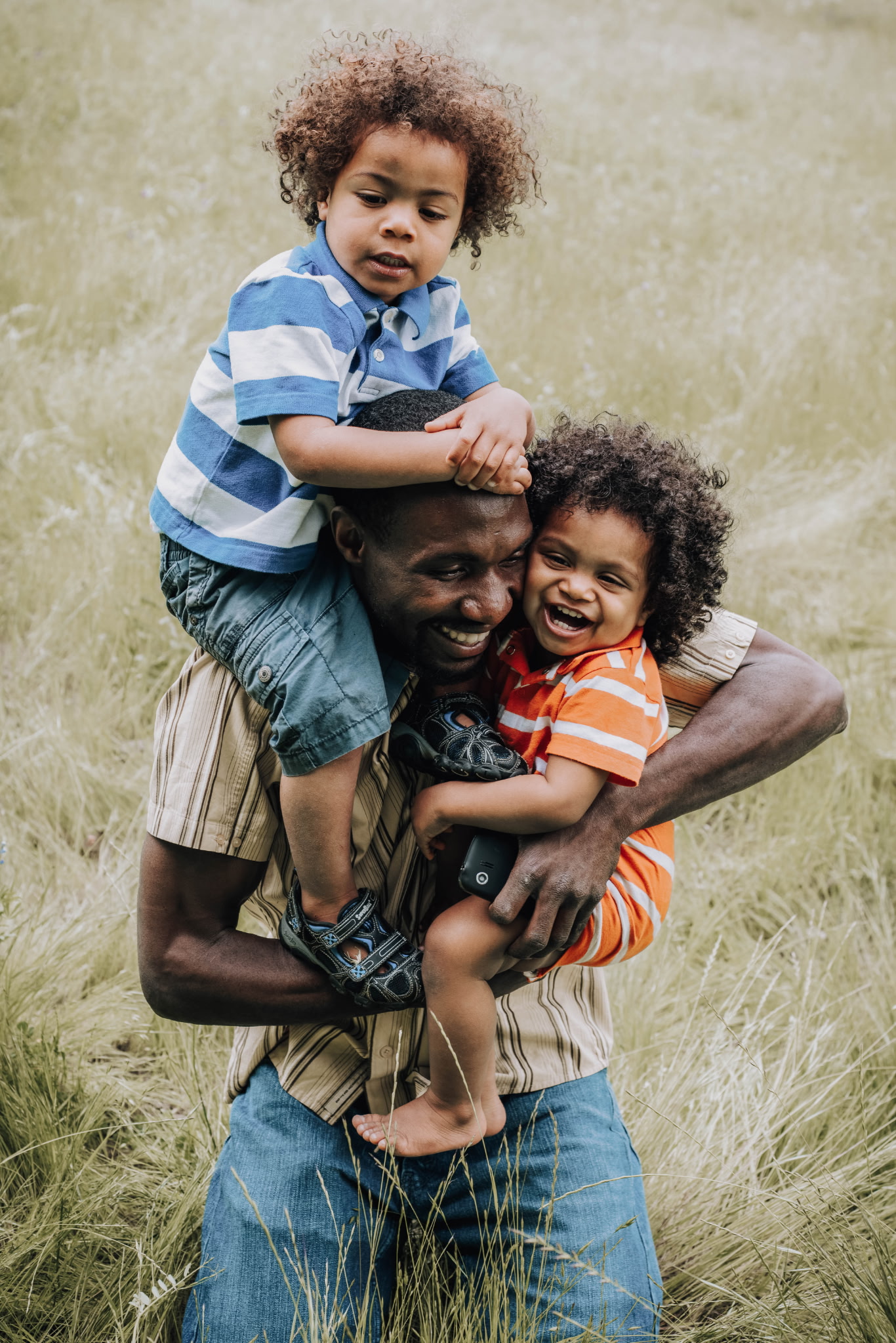 A father holding his two young children in a field