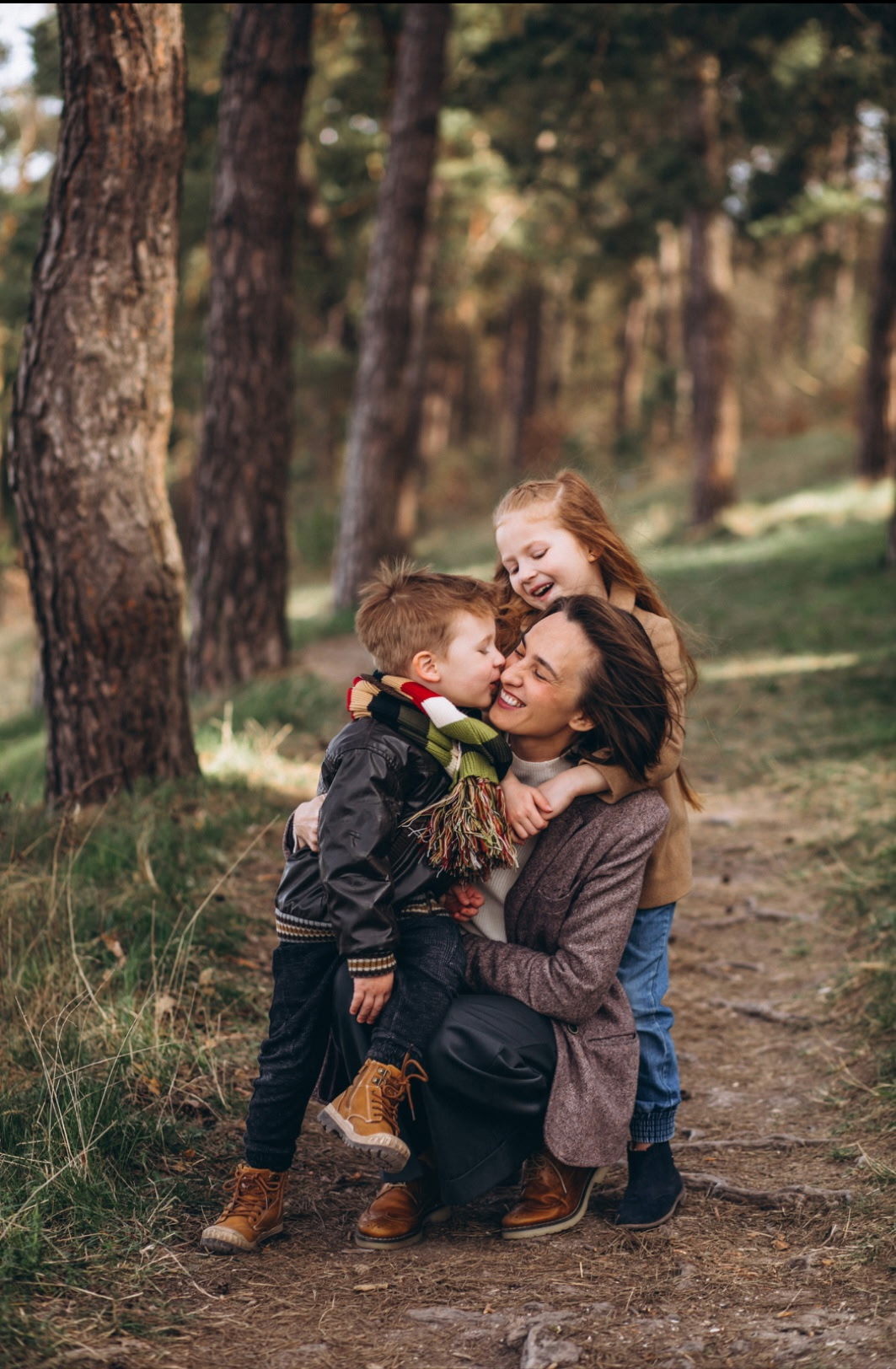 A mother embracing her two children on a wooded path